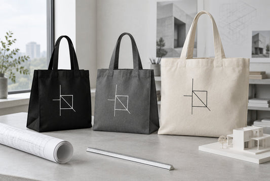 Black, graphite grey and natural tote bags with a line logo print in an architecture studio