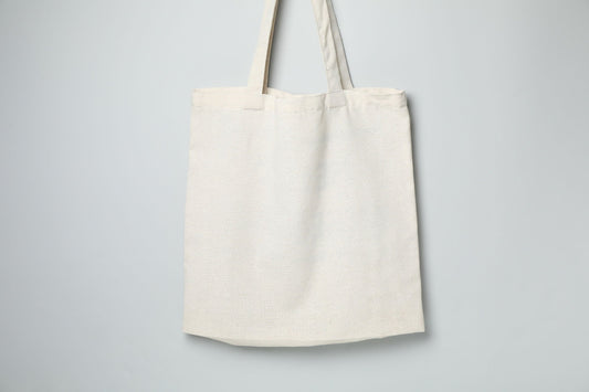 Blank natural cotton tote bag on a soft grey background, ready for a corporate welcome kit