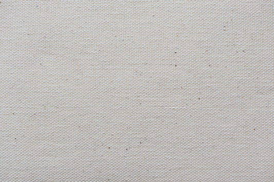 Close-up of heavyweight natural cotton canvas weave, the texture behind a premium tote bag
