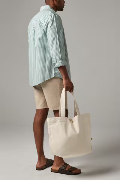 Man carrying a natural organic canvas Marina tote by its cotton webbing handles