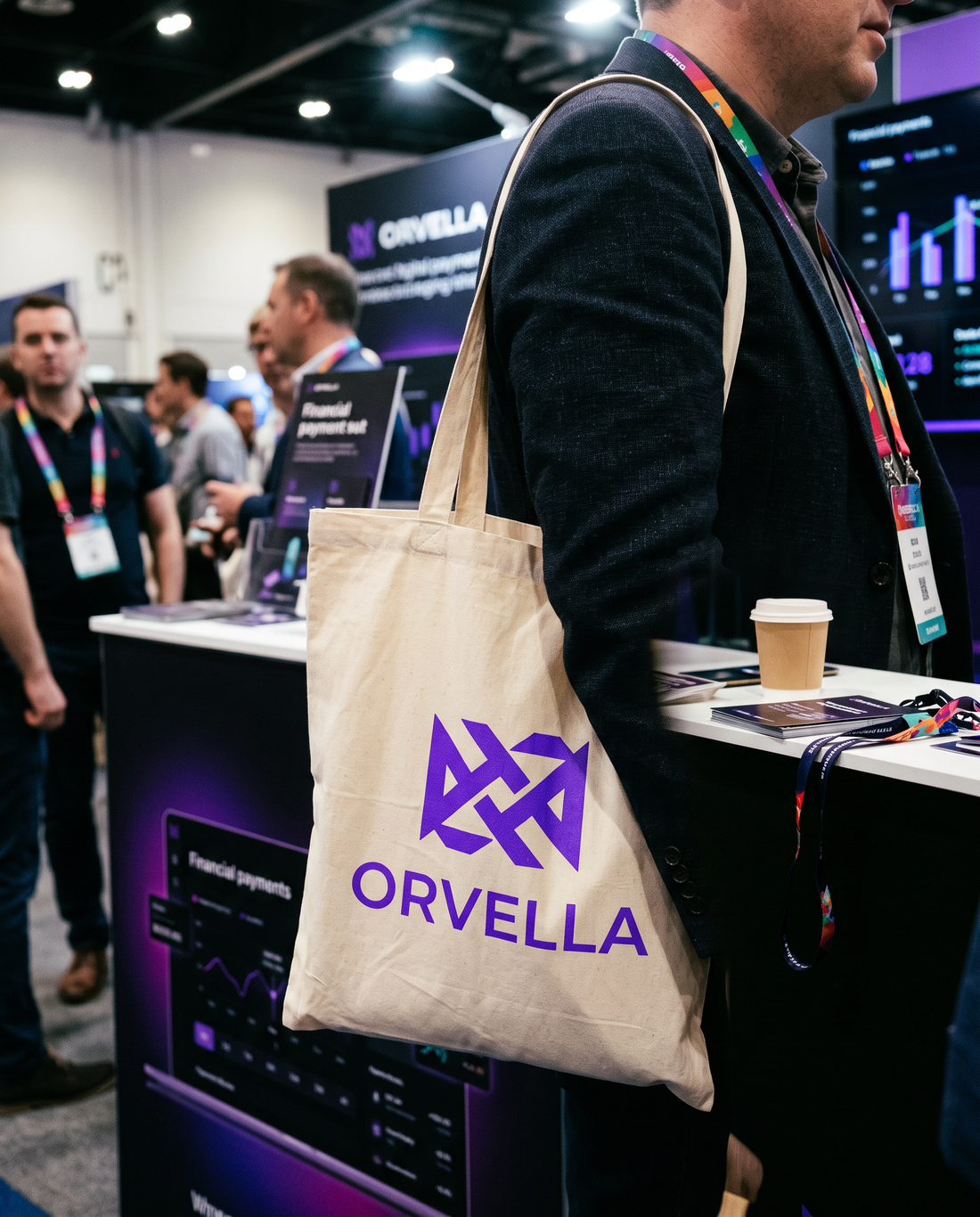 Tote bag personnalisé en coton naturel avec un logo fintech violet, porté sur un stand de conférence