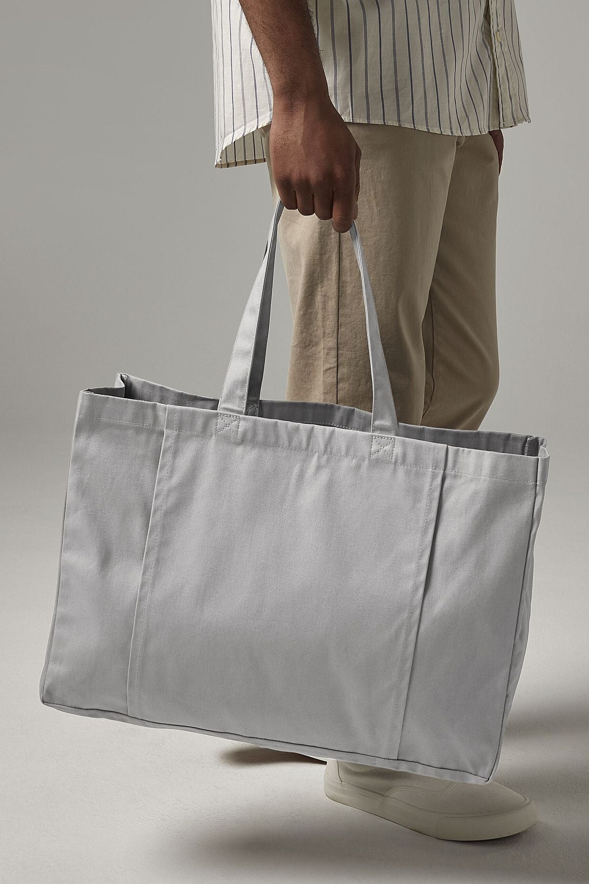Person carrying the light grey organic cotton yoga tote bag by hand