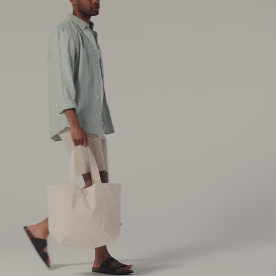 Video of a natural organic canvas Marina tote with wooden toggle, carried by hand