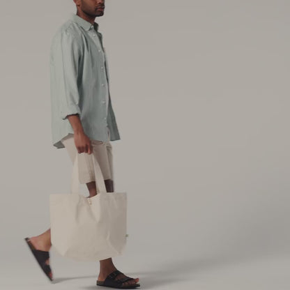 Video of a natural organic canvas Marina tote with wooden toggle, carried by hand